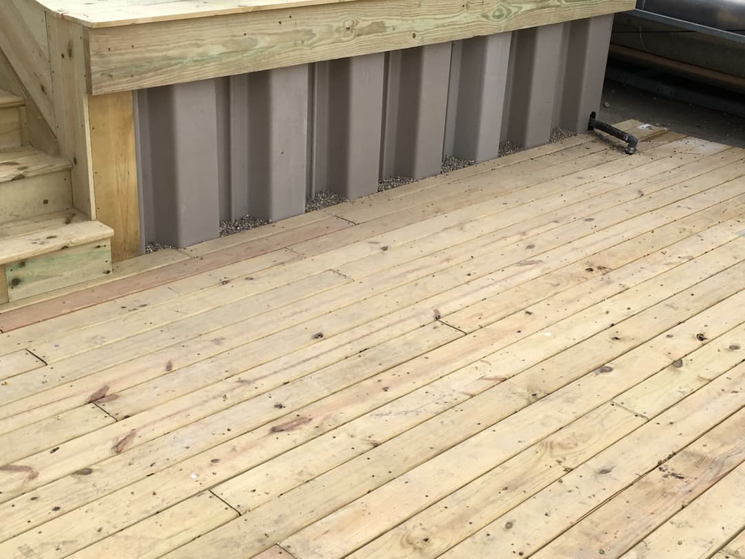 Wooden deck with steps and a metal siding wall, featuring a clean and spacious design.