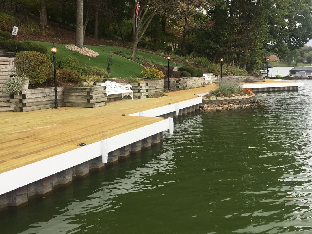 Lakefront dock with wooden walkways, benches, and landscaped shoreline.