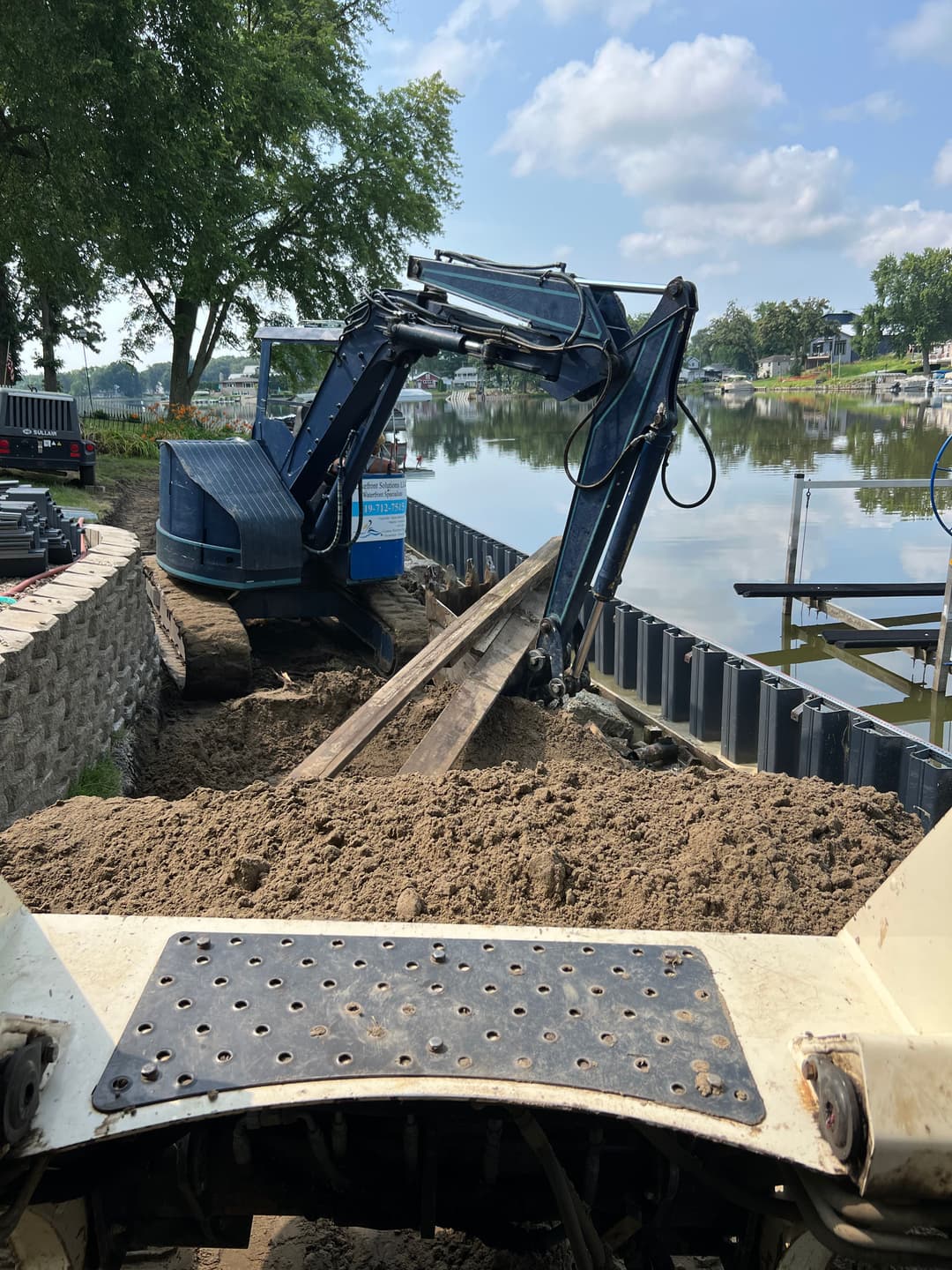 Excavator on a construction site by a river, preparing land for a project.