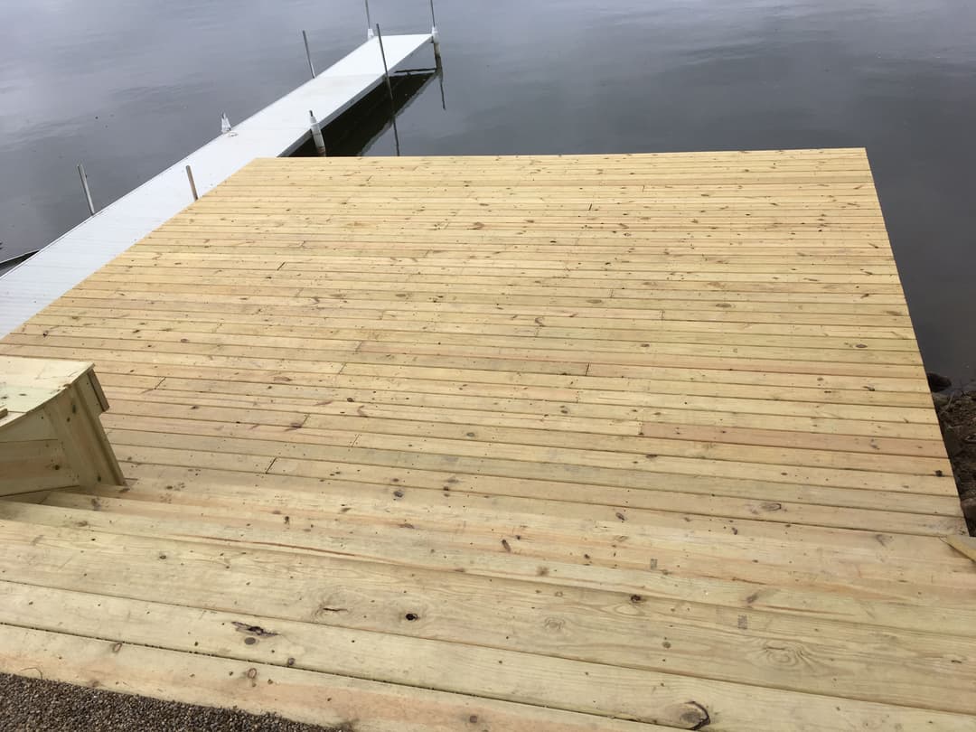 Newly built wooden dock over calm water with a clear view of the surrounding area.