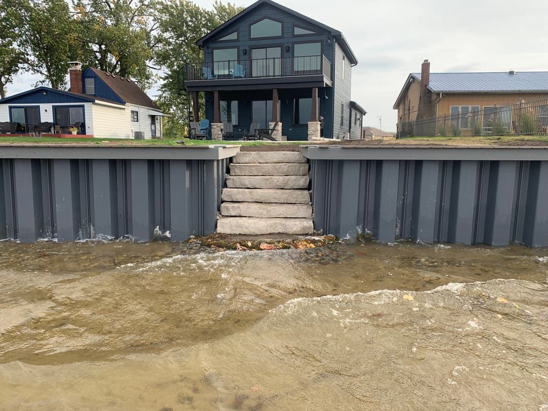 House with a modern design by the water, featuring steps leading to the shoreline.