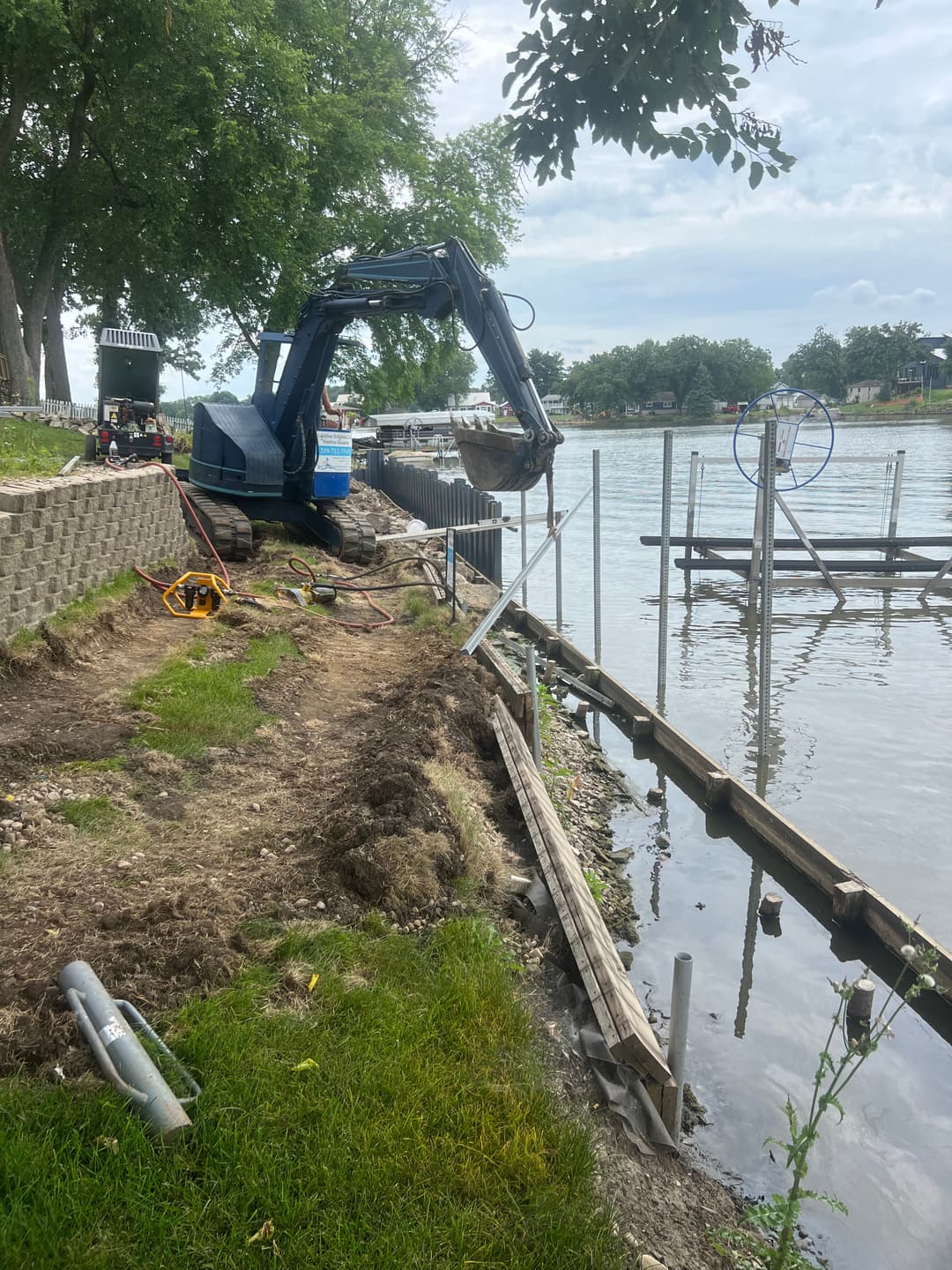 Excavator at lakeside construction site, preparing for dock installation and landscaping.