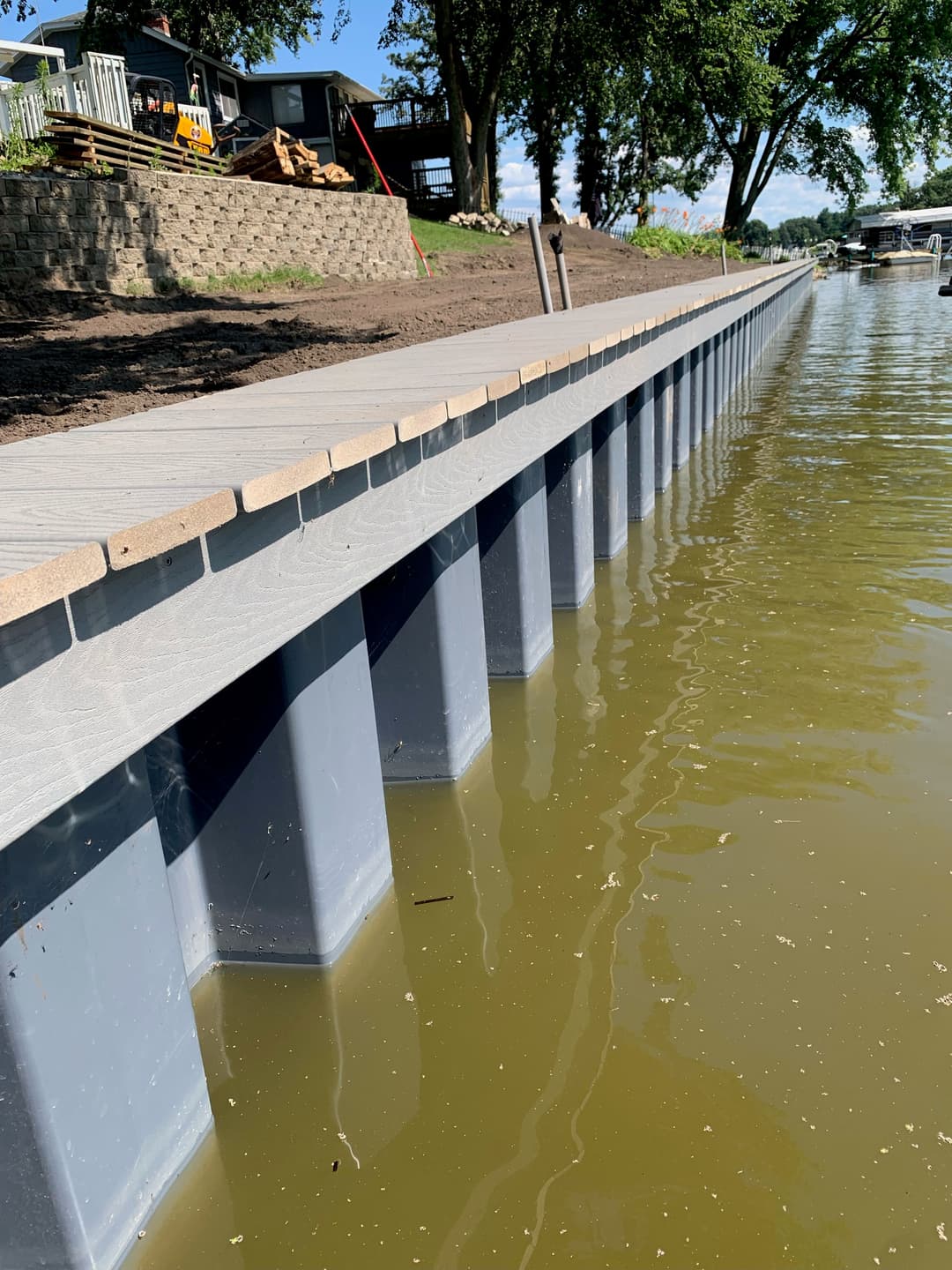 Dock on a riverbank with reflective water and trees in the background.