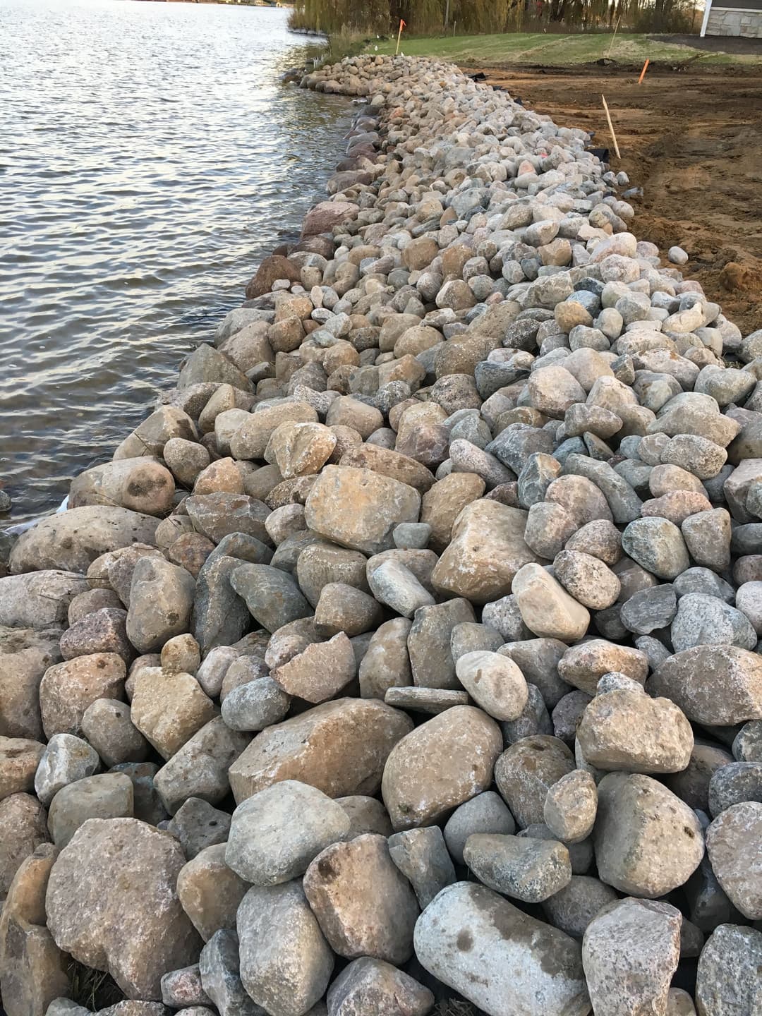 Rocky shoreline erosion control ledge along a calm body of water.