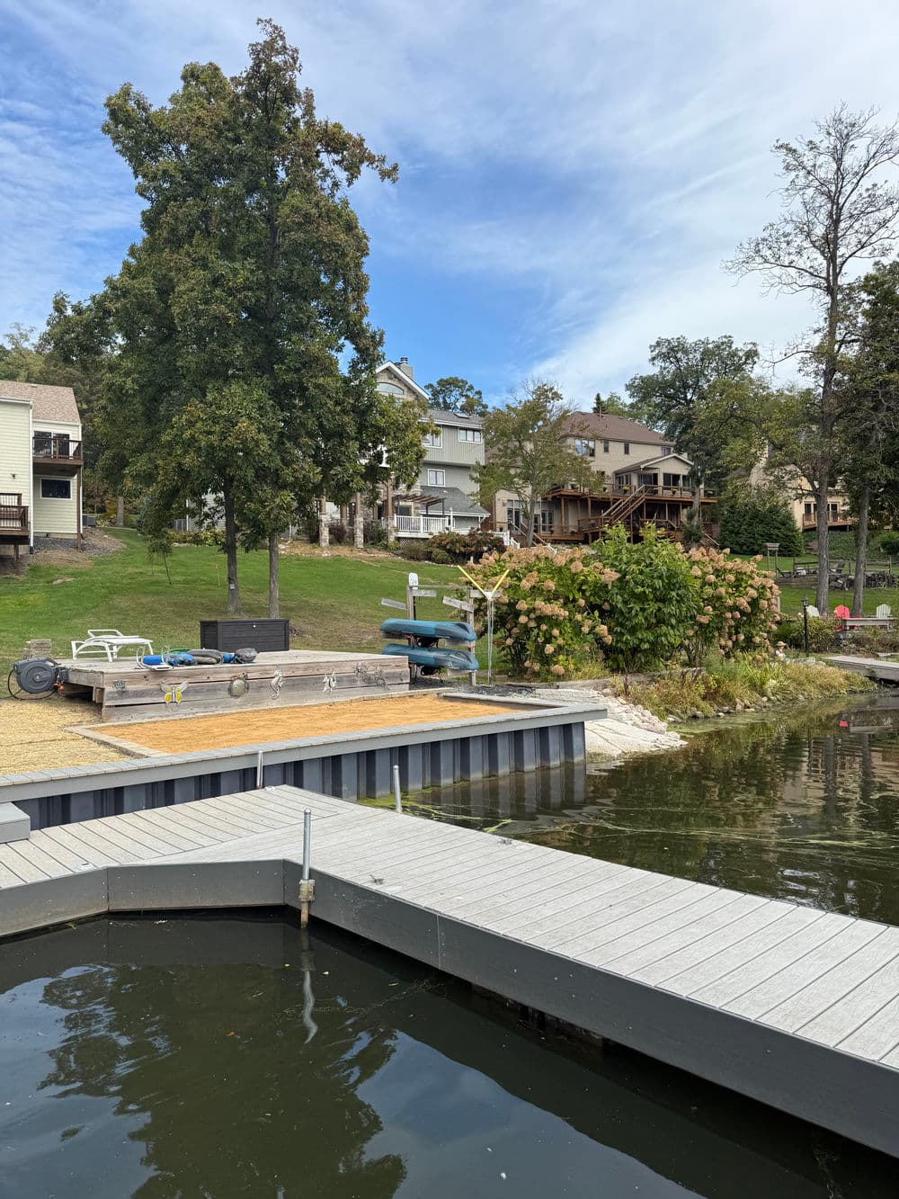 Dock by a serene lake with houses and lush greenery in the background.