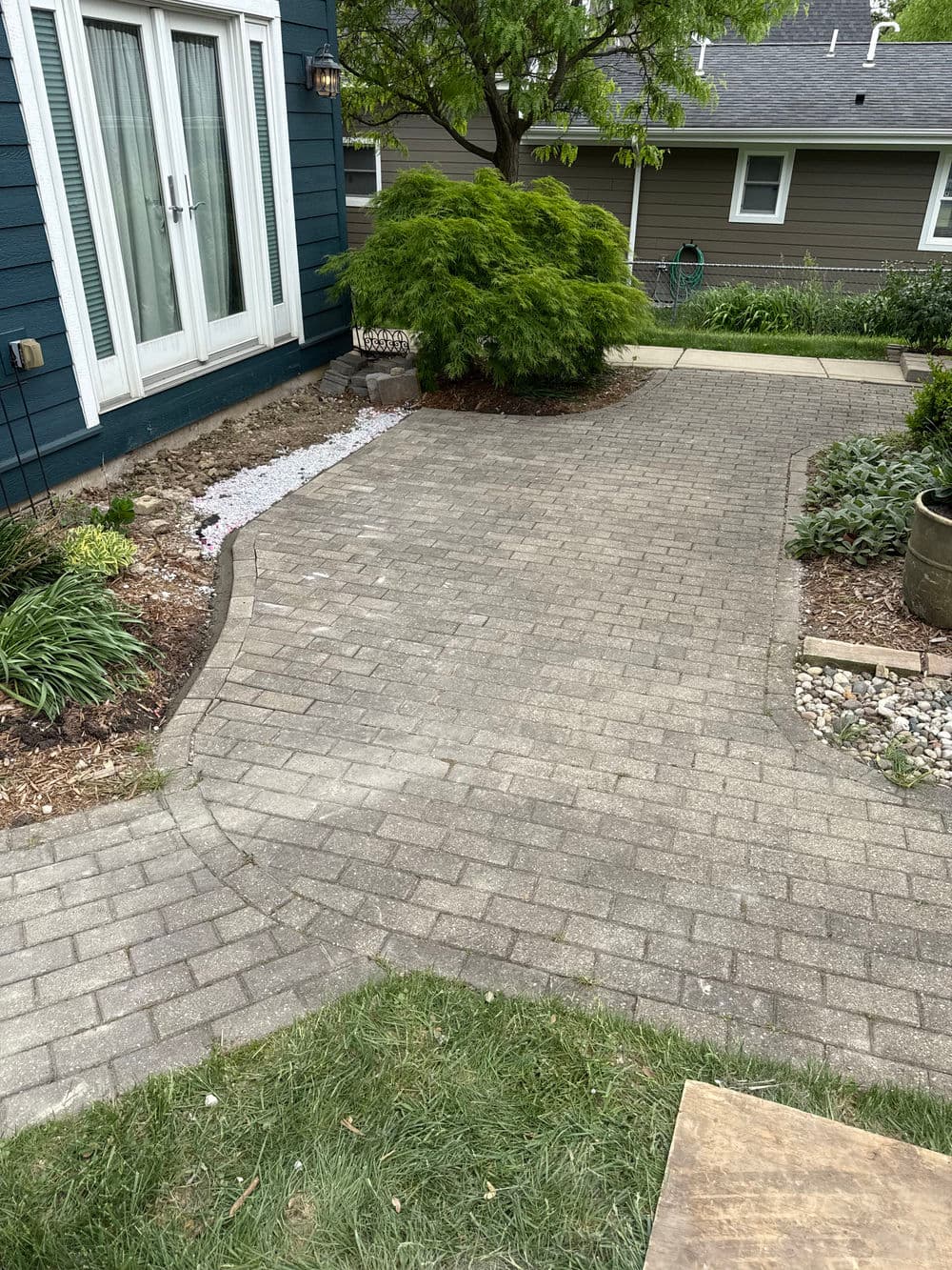 Paved pathway leading to a landscaped garden with green plants and shrubs.